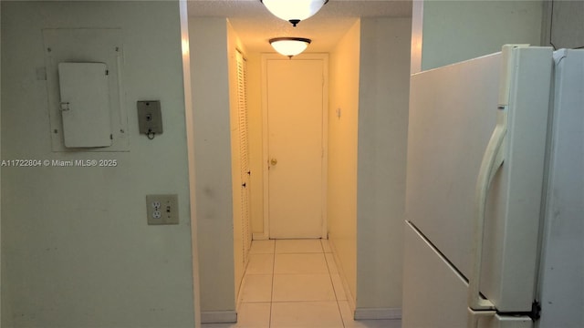 hallway featuring electric panel, a textured ceiling, and light tile patterned floors