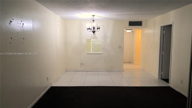 empty room featuring a textured ceiling, a chandelier, and light tile patterned flooring