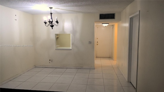 unfurnished dining area featuring a notable chandelier, light tile patterned floors, and a textured ceiling