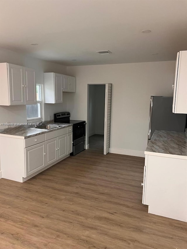 kitchen featuring white cabinets, appliances with stainless steel finishes, sink, and light wood-type flooring