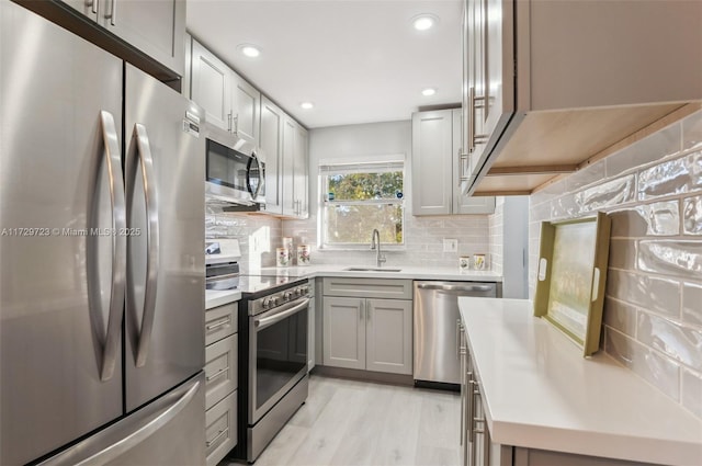 kitchen featuring tasteful backsplash, a sink, light countertops, stainless steel appliances, and gray cabinets