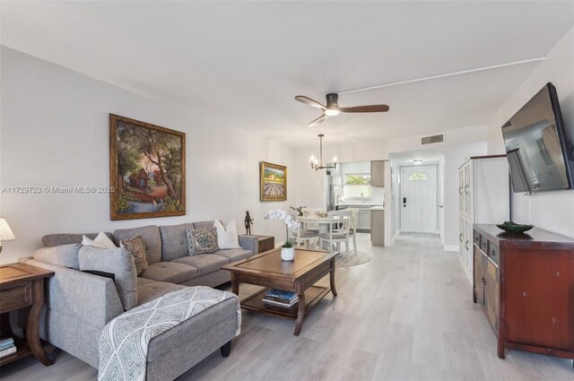 living room featuring light hardwood / wood-style floors and ceiling fan with notable chandelier