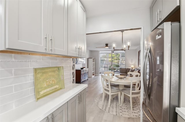 kitchen featuring white cabinets, hanging light fixtures, stainless steel fridge, and light hardwood / wood-style flooring