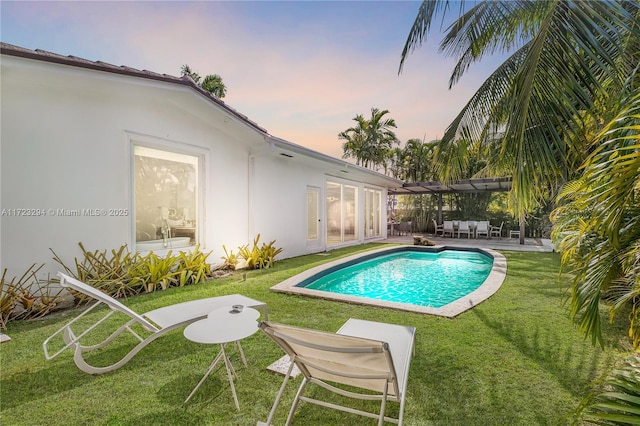 pool at dusk with a patio and a yard