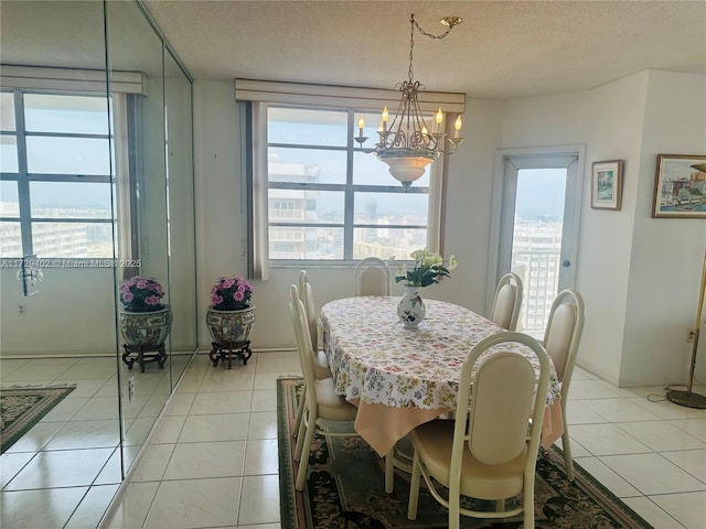 dining space with a textured ceiling, light tile patterned floors, and a chandelier