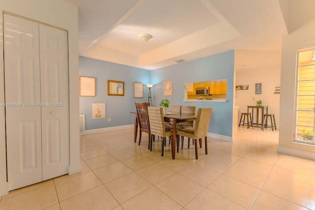 dining area featuring a raised ceiling and light tile patterned flooring