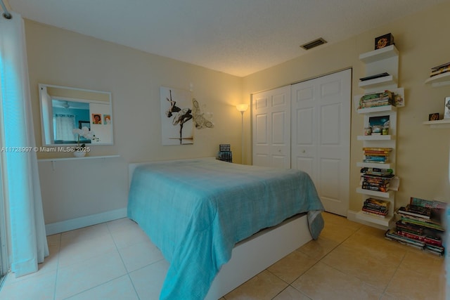 bedroom featuring a closet, light tile patterned floors, and a textured ceiling