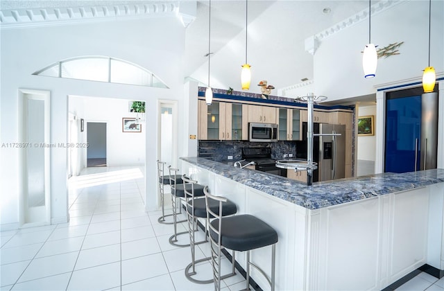 kitchen featuring kitchen peninsula, decorative light fixtures, tasteful backsplash, high vaulted ceiling, and stainless steel appliances