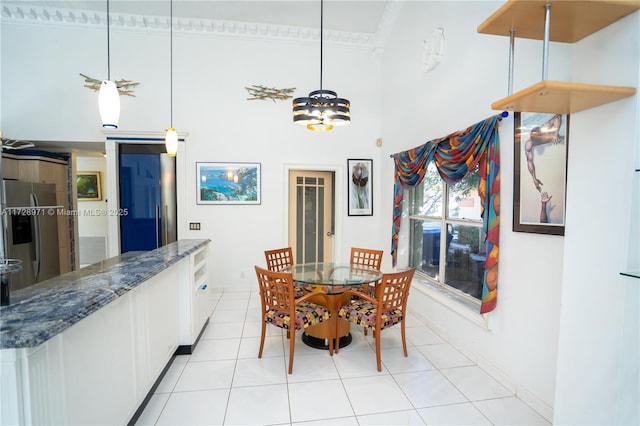 tiled dining room featuring a towering ceiling and ornamental molding