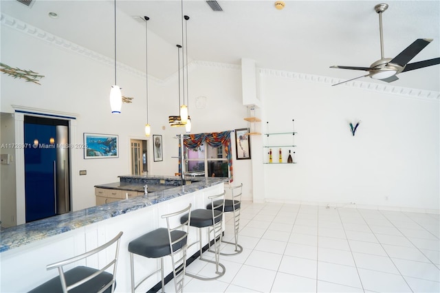 kitchen with a kitchen breakfast bar, ceiling fan, hanging light fixtures, white cabinets, and dark stone countertops