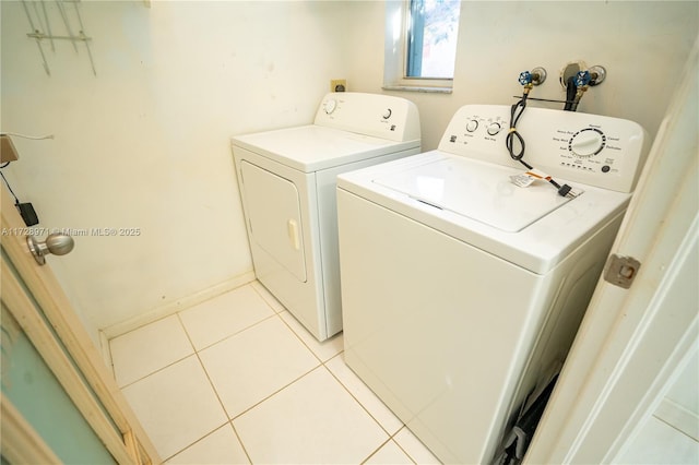 clothes washing area with light tile patterned floors and washer and dryer