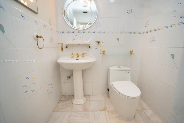 bathroom featuring toilet and tile walls