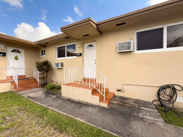 view of exterior entry with an AC wall unit