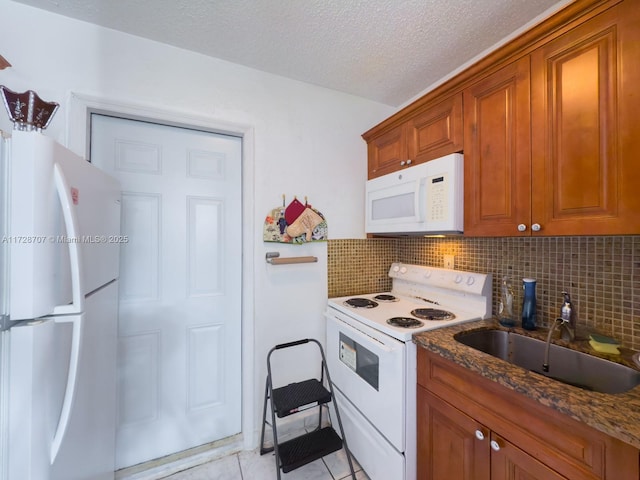 kitchen featuring white appliances, light tile patterned floors, decorative backsplash, sink, and dark stone countertops