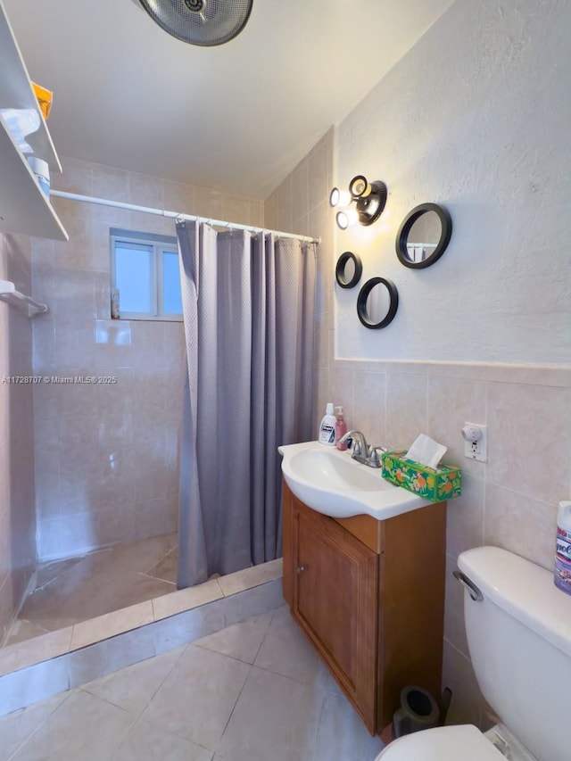 bathroom with curtained shower, tile patterned flooring, vanity, tile walls, and toilet