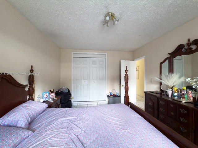 bedroom with a textured ceiling, a closet, and light tile patterned floors