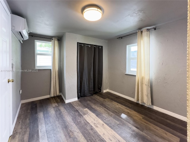 unfurnished bedroom featuring dark wood-type flooring and a wall mounted air conditioner