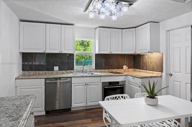 kitchen featuring appliances with stainless steel finishes, tasteful backsplash, white cabinetry, sink, and a textured ceiling