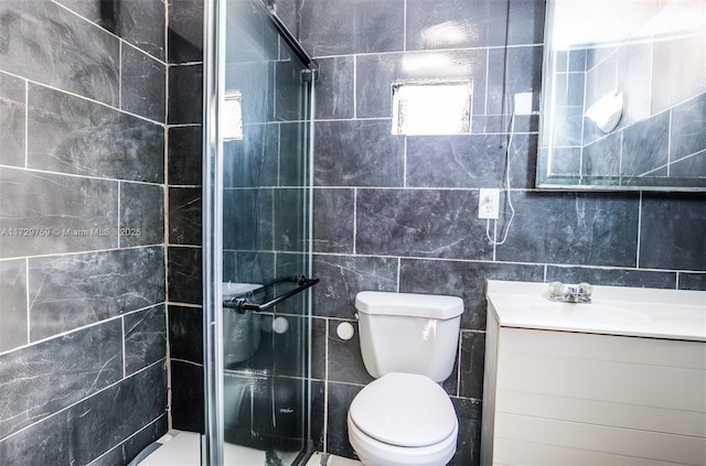 bathroom featuring vanity, a shower with door, tile walls, and toilet