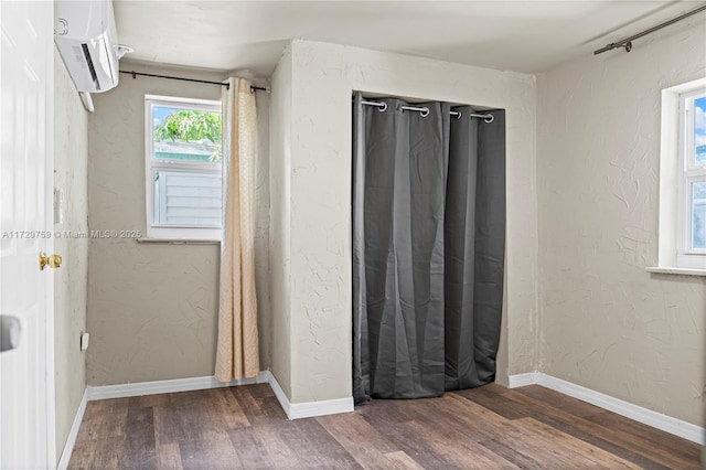 unfurnished bedroom with wood-type flooring and a wall mounted air conditioner