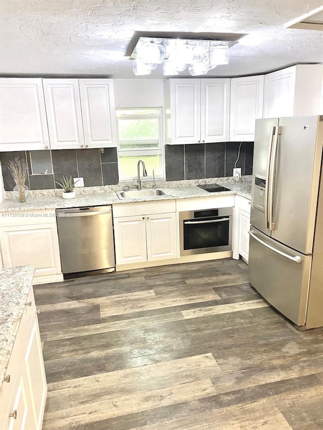 kitchen with stainless steel appliances, white cabinetry, sink, and decorative backsplash