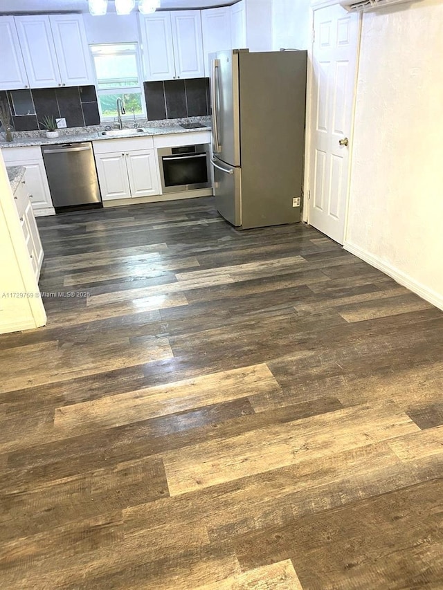 kitchen with sink, appliances with stainless steel finishes, dark hardwood / wood-style floors, tasteful backsplash, and white cabinets