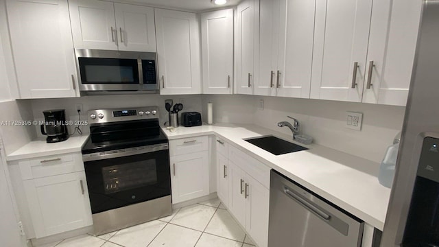 kitchen with white cabinetry, stainless steel appliances, sink, and light tile patterned floors