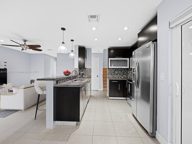 kitchen featuring appliances with stainless steel finishes, sink, pendant lighting, backsplash, and a breakfast bar area