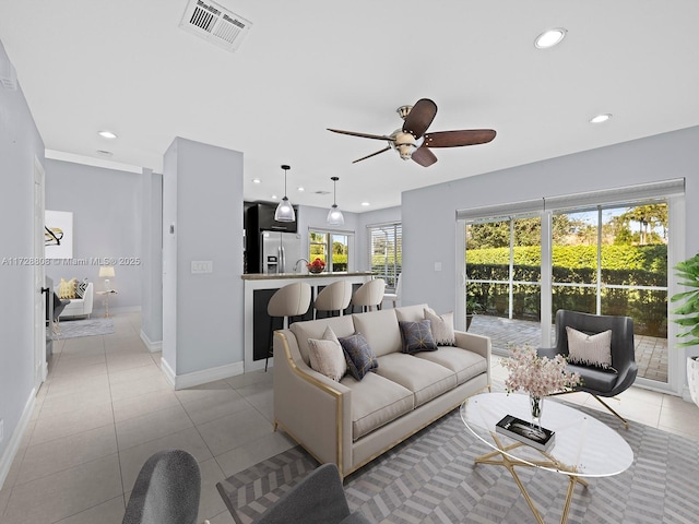 tiled living room with ceiling fan, plenty of natural light, and sink