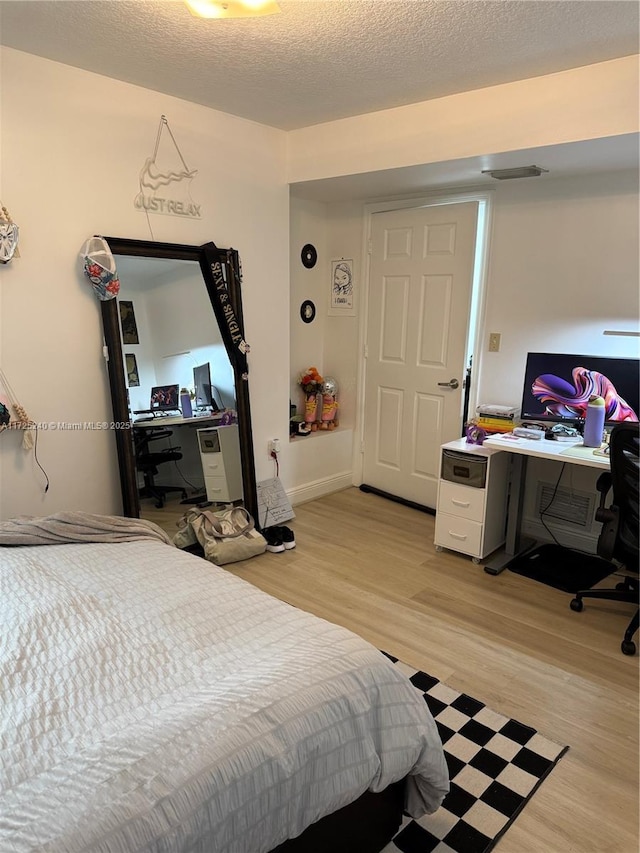 bedroom with light hardwood / wood-style flooring and a textured ceiling