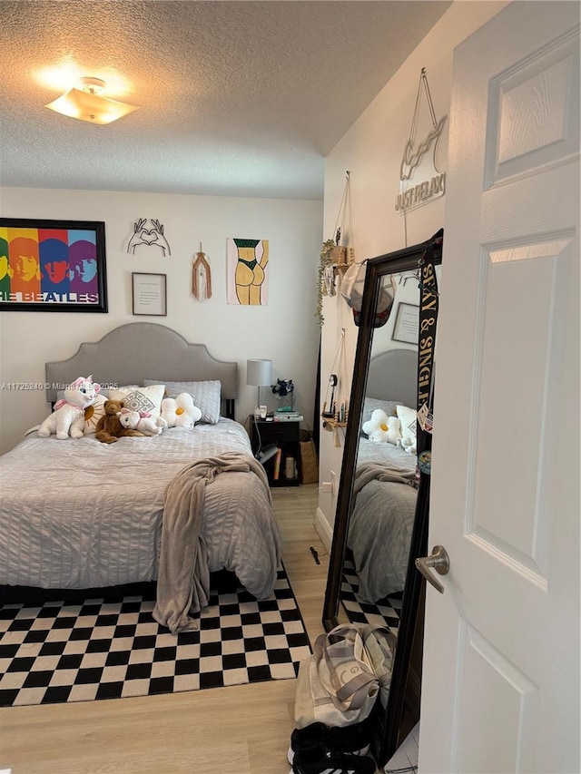 bedroom with a textured ceiling and light hardwood / wood-style flooring