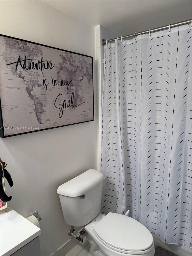 bathroom featuring tile patterned flooring, vanity, curtained shower, and toilet