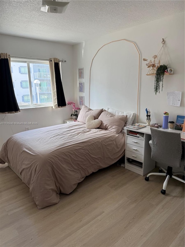 bedroom featuring light hardwood / wood-style flooring and a textured ceiling