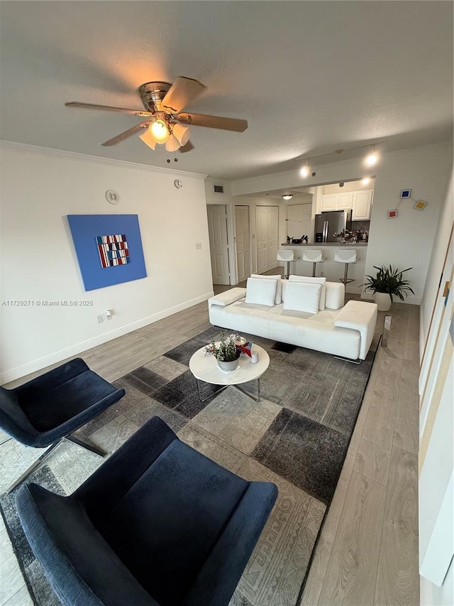 living room featuring ceiling fan, hardwood / wood-style floors, and crown molding