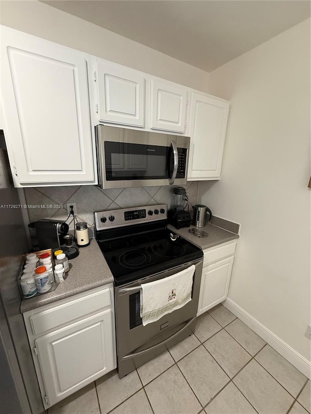 kitchen with light tile patterned floors, white cabinets, stainless steel appliances, and tasteful backsplash