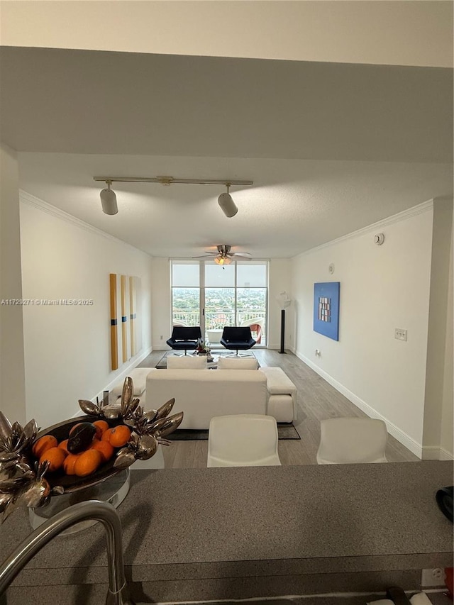 unfurnished living room with rail lighting, hardwood / wood-style flooring, ceiling fan, and crown molding