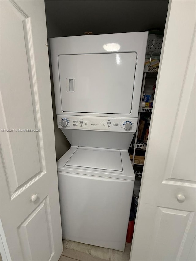 clothes washing area with light tile patterned floors and stacked washer and dryer