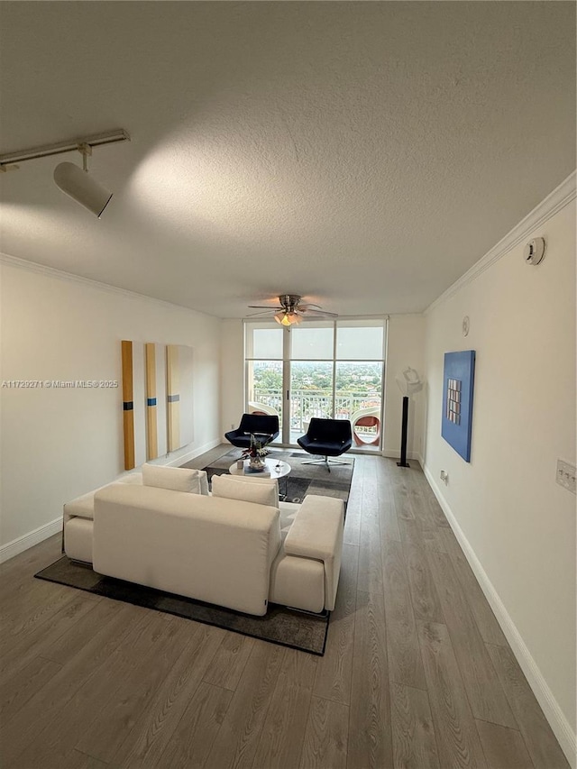 living room featuring ceiling fan, hardwood / wood-style floors, a textured ceiling, expansive windows, and ornamental molding