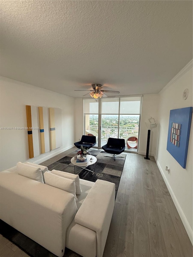 living room with a wall of windows, hardwood / wood-style floors, ornamental molding, and a textured ceiling