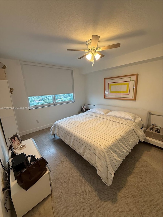 bedroom with ceiling fan, a textured ceiling, and wood-type flooring