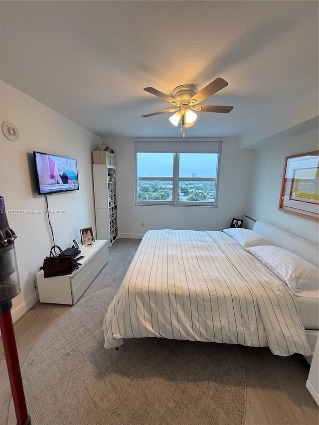 bedroom with hardwood / wood-style flooring, a textured ceiling, and ceiling fan