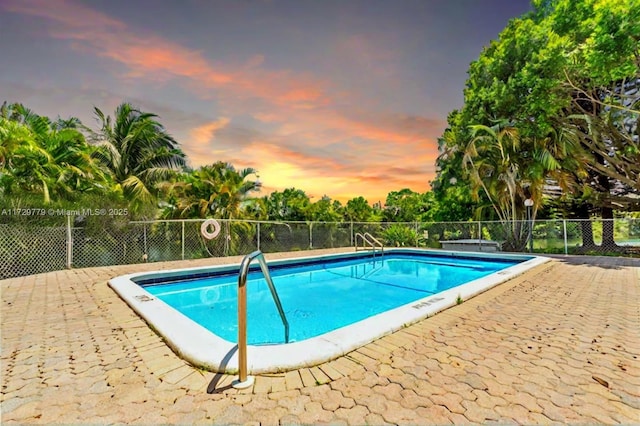 pool at dusk featuring a patio area