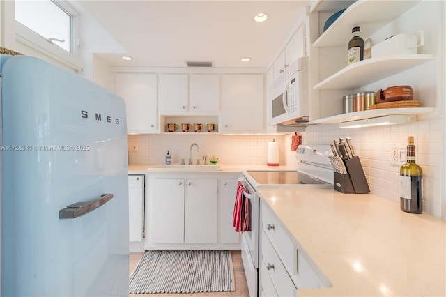 kitchen with sink, white appliances, tasteful backsplash, and white cabinets