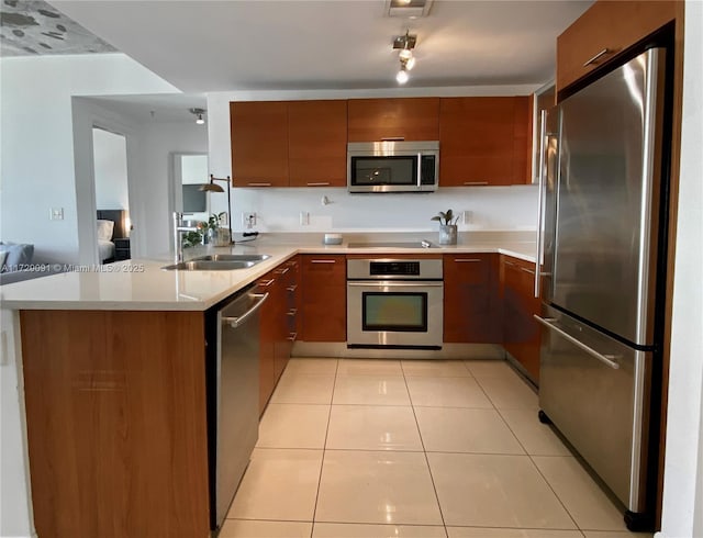 kitchen featuring sink, kitchen peninsula, light tile patterned floors, and appliances with stainless steel finishes