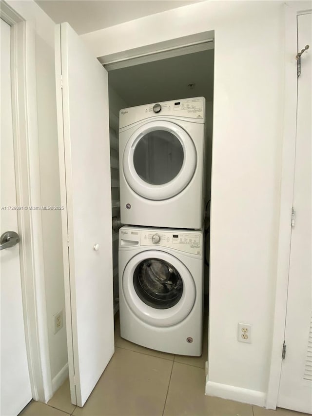 laundry room featuring stacked washer / drying machine and light tile patterned floors