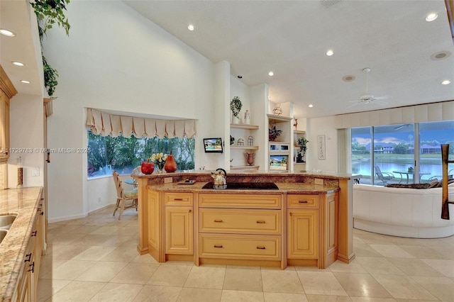 kitchen with ceiling fan, light tile patterned floors, light stone countertops, and light brown cabinets