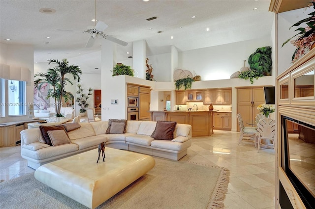 tiled living room featuring sink, a high ceiling, and a textured ceiling