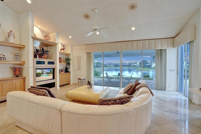 living room featuring ceiling fan, a wealth of natural light, built in shelves, and a textured ceiling