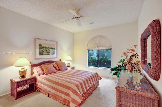 carpeted bedroom featuring ceiling fan and a textured ceiling