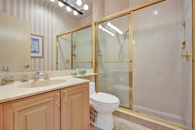 bathroom with a shower with shower door, toilet, vanity, and tile patterned flooring